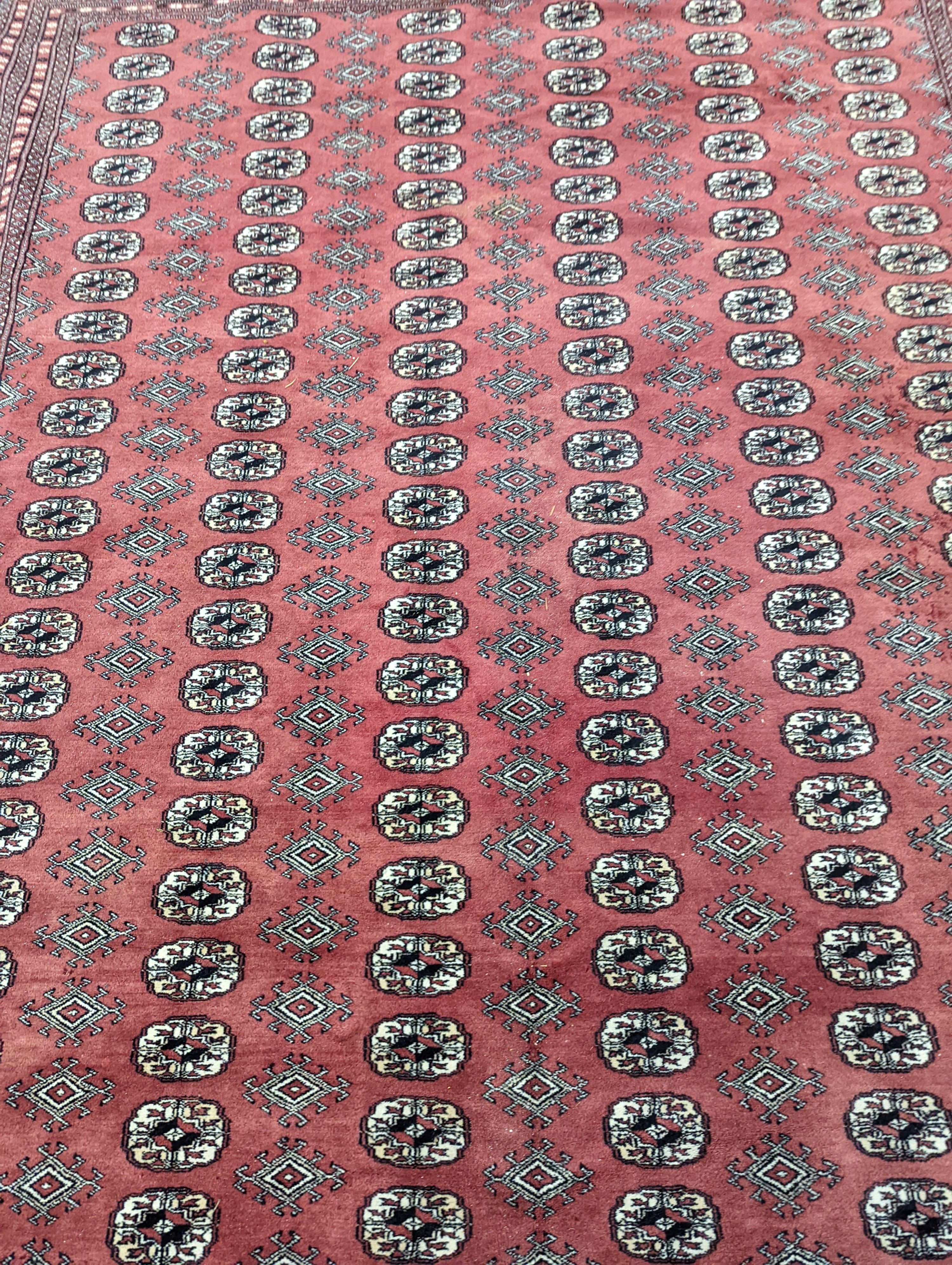 A Bokhara burgundy ground carpet, 360 x 276cm